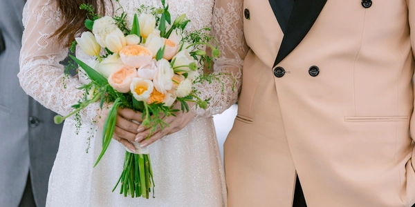 Close-up of a bride's bouquet and a groom's peach-toned jacket lapel