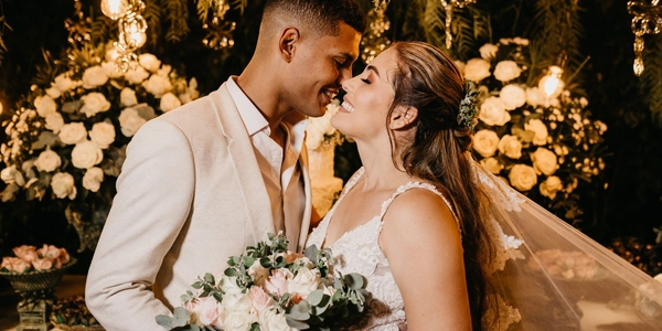 Newlyweds embracing at their reception, surrounded by warm string lights and florals