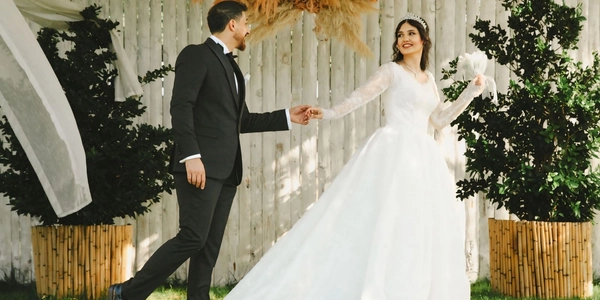 A couple walking hand in hand at a rustic Hill Country wedding venue framed by a wooden fence