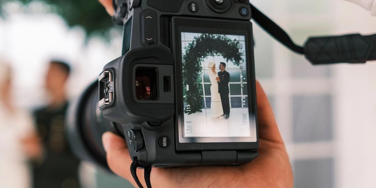 A wedding photographer reviewing a shot of the couple through the camera's viewfinder