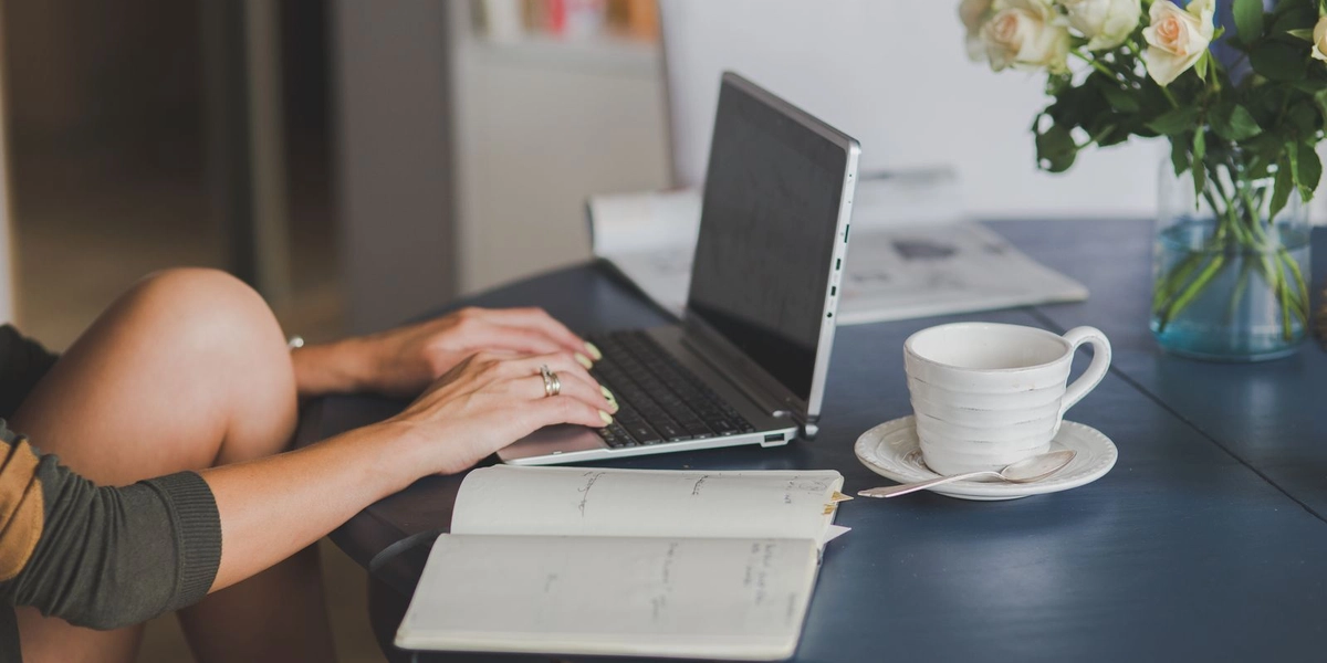 A small business owner working from a home office with a laptop and fresh roses on the table